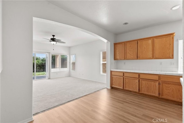 4349 Bethpage Dr, Palmdale, CA 93551 - kitchen featuring light wood-style flooring, a ceiling fan, arched walkways, open floor plan, and brown cabinets