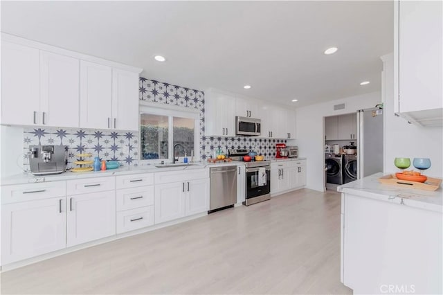 741 W Wedgewood Ln, La Habra, CA 90631 - kitchen featuring appliances with stainless steel finishes, separate washer and dryer, backsplash, a sink, and white cabinetry