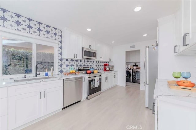 741 W Wedgewood Ln, La Habra, CA 90631 - kitchen featuring stainless steel appliances, a sink, separate washer and dryer, white cabinets, and light stone counters
