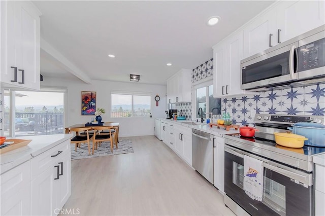 741 W Wedgewood Ln, La Habra, CA 90631 - kitchen featuring appliances with stainless steel finishes, a sink, decorative backsplash, light wood-style flooring, and white cabinets