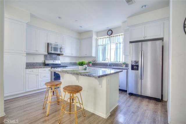 12456 Cassiopeia Ct, Eastvale, CA 91752 - kitchen featuring stainless steel appliances, light wood-type flooring, white cabinetry, a breakfast bar area, and recessed lighting