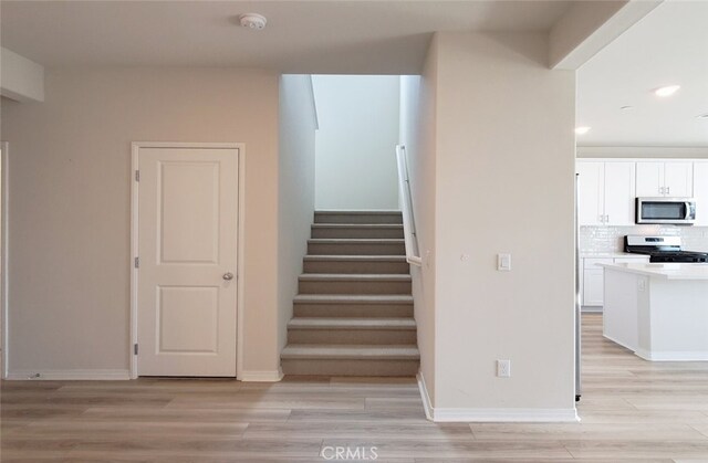 24311 Insignia Dr, Menifee, CA 92584 - stairs featuring wood finished floors, recessed lighting, and baseboards