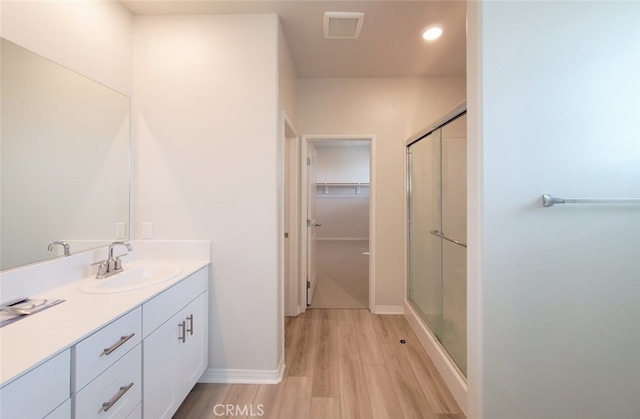 24311 Insignia Dr, Menifee, CA 92584 - bathroom with vanity, wood finished floors, a shower with shower door, a spacious closet, and recessed lighting