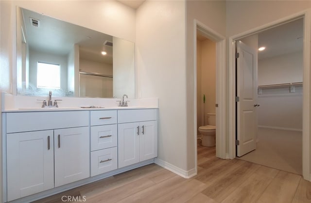 24311 Insignia Dr, Menifee, CA 92584 - full bathroom featuring wood finished floors, double vanity, toilet, a shower with door, and baseboards