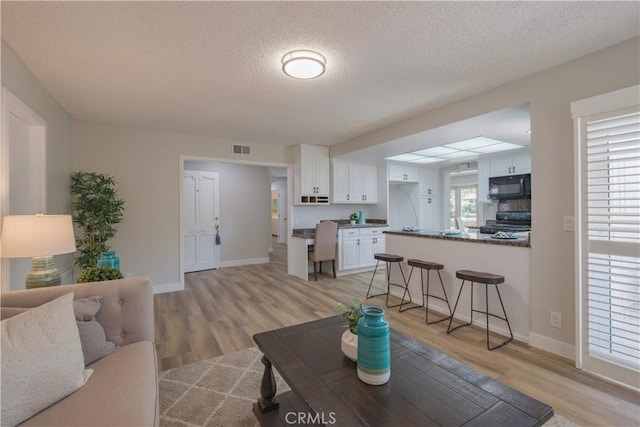 1506 W Sharon Rd, Santa Ana, CA 92706 - living room with light wood finished floors, a textured ceiling, and baseboards