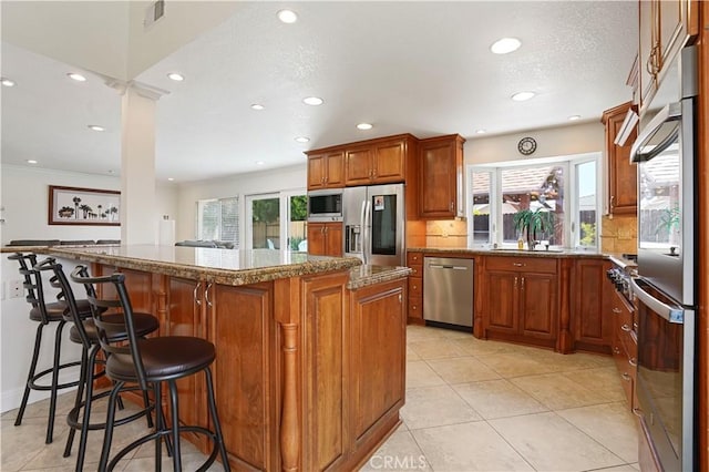 17882 Hallcroft Ln, Huntington Beach, CA 92647 - kitchen with stainless steel appliances, brown cabinets, tasteful backsplash, recessed lighting, and a kitchen breakfast bar