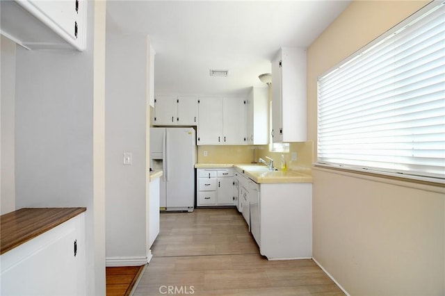 5655 Wish Ave, Encino, CA 91316 - kitchen with white refrigerator with ice dispenser, light wood-type flooring, plenty of natural light, and white cabinets