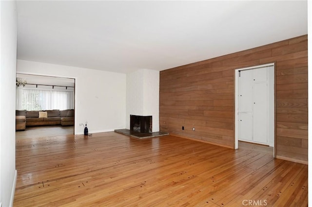 5655 Wish Ave, Encino, CA 91316 - unfurnished living room featuring wood walls, light wood-style floors, and a large fireplace