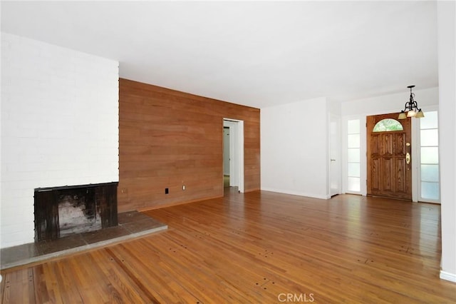 5655 Wish Ave, Encino, CA 91316 - unfurnished living room featuring wood finished floors, a chandelier, a fireplace, and wooden walls