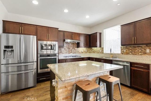 29463 Bouris Dr, Menifee, CA 92584 - kitchen featuring appliances with stainless steel finishes, a sink, under cabinet range hood, a center island, and backsplash