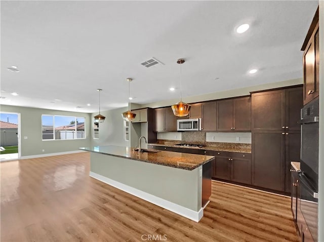 27117 Great Plains Ct, Menifee, CA 92585 - kitchen featuring stainless steel microwave, gas stovetop, a sink, dark brown cabinetry, and light wood finished floors