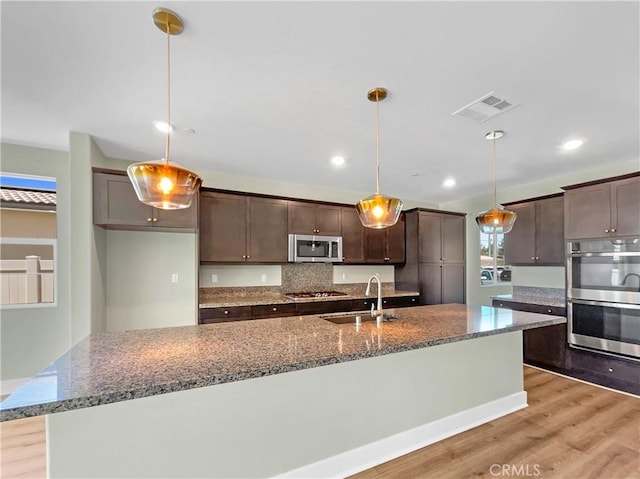 27117 Great Plains Ct, Menifee, CA 92585 - kitchen featuring stainless steel appliances, a sink, dark brown cabinets, light wood-style floors, and recessed lighting