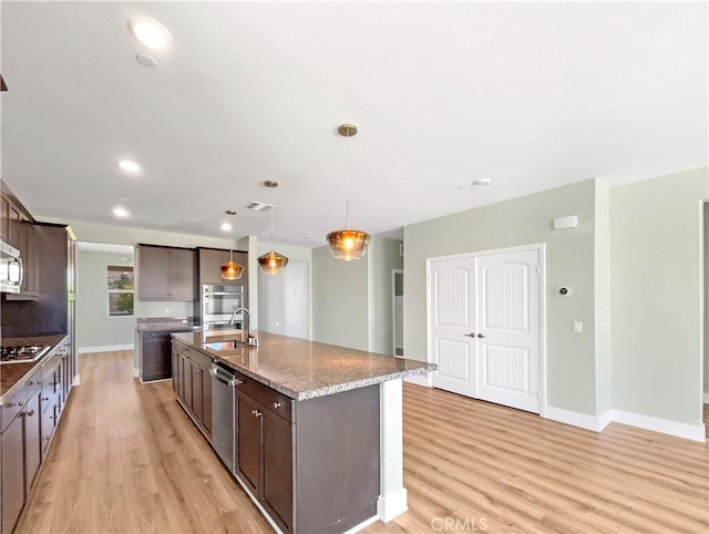 27117 Great Plains Ct, Menifee, CA 92585 - kitchen featuring a sink, light wood-style floors, stainless steel appliances, dark brown cabinetry, and a center island with sink
