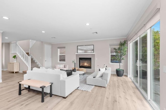 13403 Hudson Ln, San Diego, CA 92130 - living room featuring light wood-style flooring, a warm lit fireplace, recessed lighting, ornamental molding, and stairs