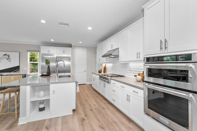 13403 Hudson Ln, San Diego, CA 92130 - kitchen featuring stainless steel appliances, under cabinet range hood, ornamental molding, backsplash, and white cabinetry