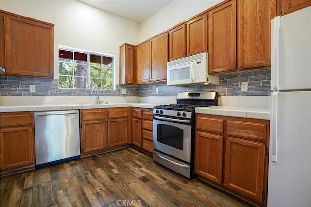 3690 S Bear St Unit 5, Santa Ana, CA 92704 - kitchen featuring stainless steel appliances, a sink, dark wood-type flooring, decorative backsplash, and brown cabinetry