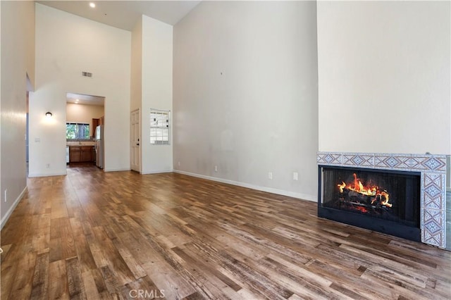 3690 S Bear St Unit 5, Santa Ana, CA 92704 - unfurnished living room with high vaulted ceiling, wood finished floors, baseboards, and a fireplace