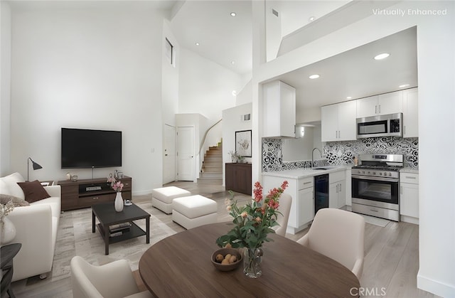 11150 Glenoaks Blvd Unit 106, Pacoima, CA 91331 - living room featuring stairway, light wood-style flooring, high vaulted ceiling, recessed lighting, and baseboards