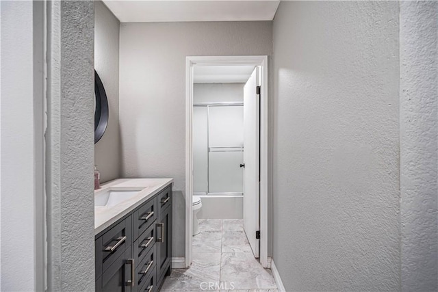 14819 Downey Ave Unit 121, Paramount, CA 90723 - full bath featuring vanity, marble finish flooring, a textured wall, toilet, and combined bath / shower with glass door