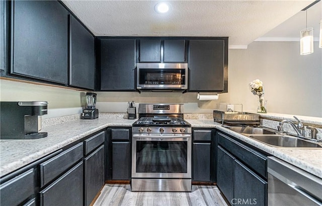 14819 Downey Ave Unit 121, Paramount, CA 90723 - kitchen with appliances with stainless steel finishes, crown molding, light countertops, light wood-style floors, and a sink
