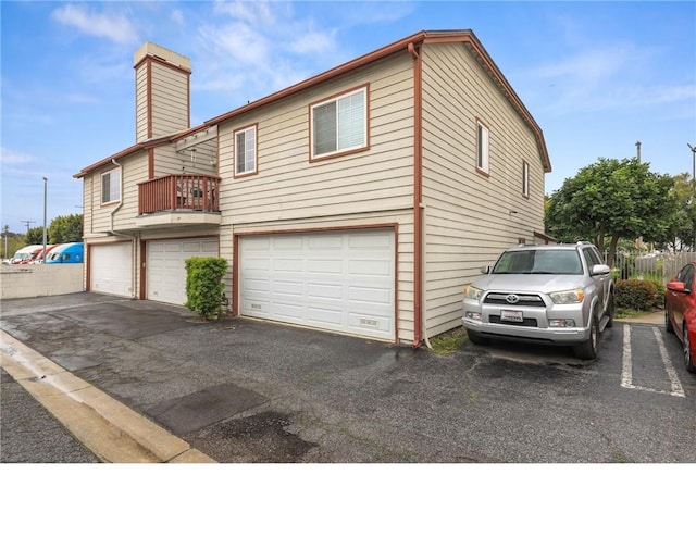 25520 Dodge Ave Unit A, Harbor City, CA 90710 - view of side of home featuring a garage, a chimney, a balcony, and driveway