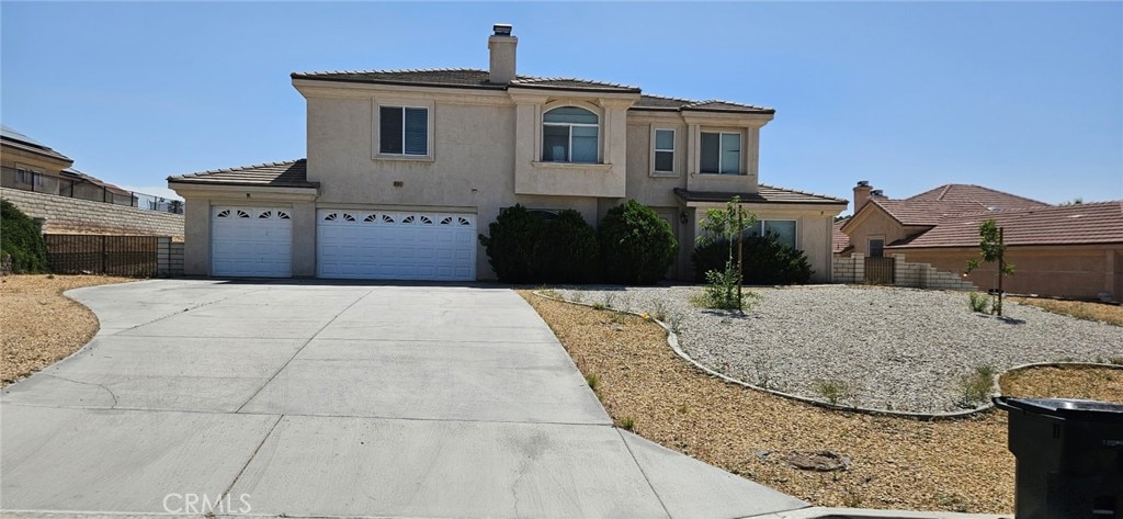 16245 Ridge View Dr, Apple Valley, CA 92307 - mediterranean / spanish-style home with concrete driveway, a chimney, stucco siding, a garage, and a tiled roof