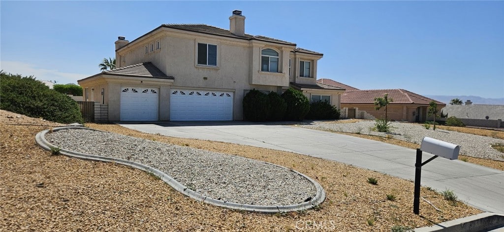 16245 Ridge View Dr, Apple Valley, CA 92307 - view of front of property featuring concrete driveway, a garage, stucco siding, and a chimney