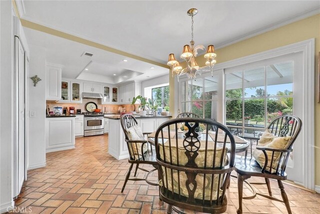 6232 E Shenandoah Ave, Orange, CA 92867 - dining space with a chandelier, a tray ceiling, brick flooring, ornamental molding, and recessed lighting