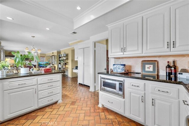 6232 E Shenandoah Ave, Orange, CA 92867 - kitchen featuring stainless steel microwave, ornamental molding, a chandelier, white cabinets, and decorative backsplash
