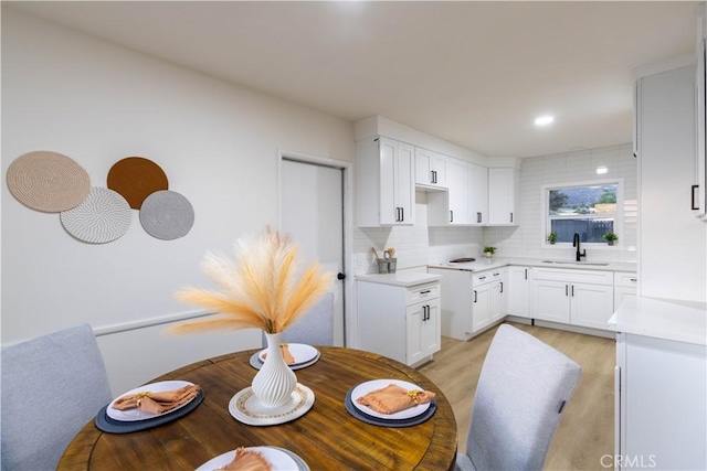 12563 3rd St, Yucaipa, CA 92399 - kitchen with light wood-style flooring, backsplash, white cabinetry, and a sink