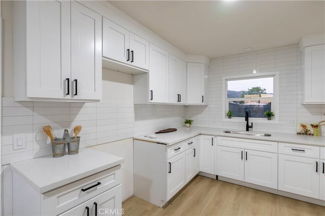 12563 3rd St, Yucaipa, CA 92399 - kitchen featuring a sink, tasteful backsplash, light countertops, white cabinets, and light wood-type flooring
