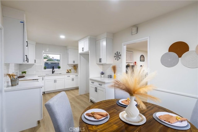 12563 3rd St, Yucaipa, CA 92399 - kitchen featuring a sink, tasteful backsplash, light countertops, white cabinets, and light wood-style flooring