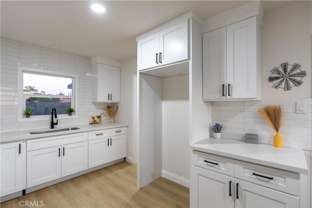 12563 3rd St, Yucaipa, CA 92399 - kitchen with a sink, backsplash, light wood-type flooring, white cabinetry, and light countertops