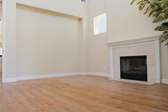 7040 Whitewater St, Carlsbad, CA 92011 - unfurnished living room featuring wood finished floors, a high ceiling, and a tiled fireplace