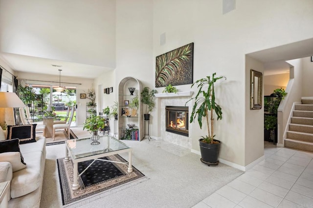 6839 Caminito Sueno, Carlsbad, CA 92009 - carpeted living room with a towering ceiling, a glass covered fireplace, stairs, tile patterned flooring, and baseboards