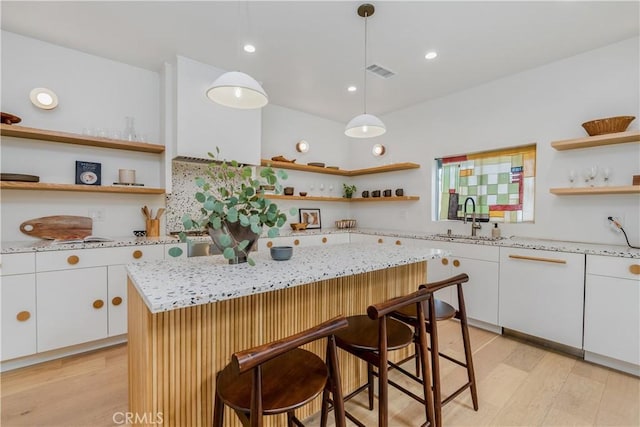 2240 Ewing St, Los Angeles, CA 90039 - kitchen featuring open shelves, light wood finished floors, white cabinetry, a kitchen breakfast bar, and decorative light fixtures