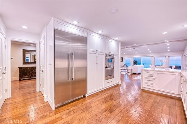 1155 Katella St, Laguna Beach, CA 92651 - kitchen with stainless steel appliances, white cabinets, light wood-type flooring, recessed lighting, and open floor plan