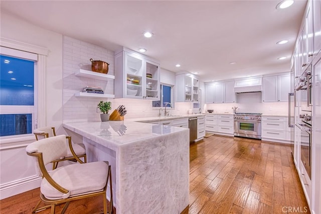 1155 Katella St, Laguna Beach, CA 92651 - kitchen with appliances with stainless steel finishes, a peninsula, a sink, white cabinets, and light wood-style flooring
