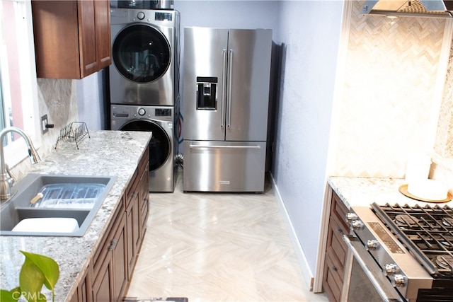 1831 W 68th St, Los Angeles, CA 90047 - kitchen featuring stainless steel appliances, a sink, stacked washing machine and dryer, baseboards, and brown cabinetry