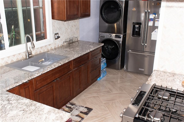 1831 W 68th St, Los Angeles, CA 90047 - kitchen with stainless steel appliances, a sink, stacked washer / drying machine, backsplash, and light stone counters