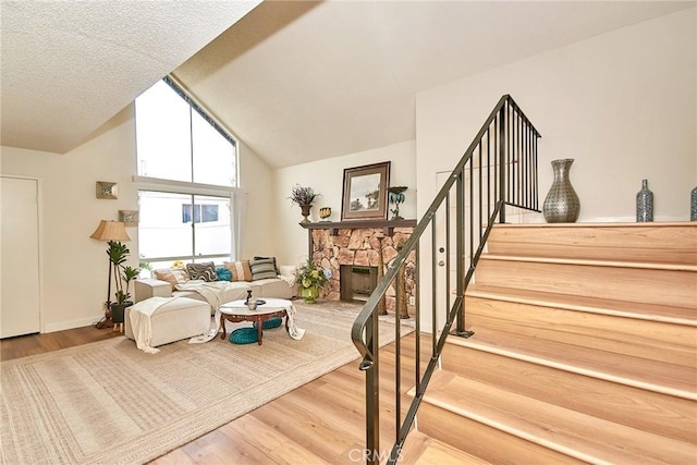 4838 Elrovia Ave Unit E, El Monte, CA 91732 - living room featuring wood finished floors, stairway, lofted ceiling, and a stone fireplace