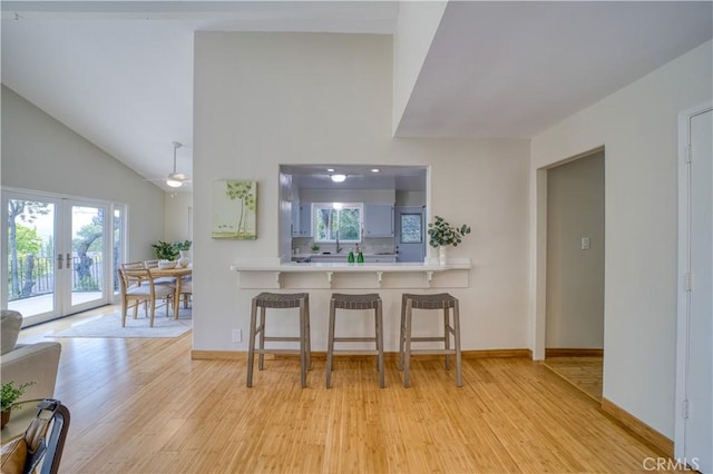 1770 Alrita St, San Luis Obispo, CA 93401 - kitchen featuring light wood finished floors, french doors, a kitchen breakfast bar, light countertops, and a towering ceiling