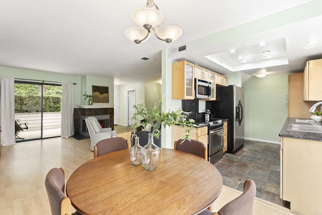 4535 Chateau Dr, San Diego, CA 92117 - dining area with baseboards, a tiled fireplace, a raised ceiling, and a chandelier