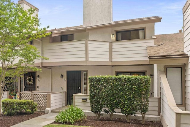4535 Chateau Dr, San Diego, CA 92117 - view of front facade with a balcony, a chimney, stucco siding, and a porch