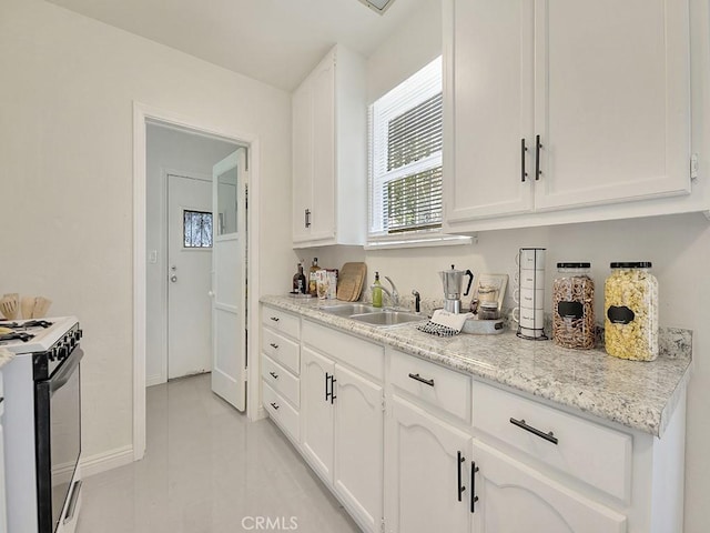 8830 Ruthelen St, Los Angeles, CA 90047 - kitchen with white gas stove, a sink, white cabinets, light tile patterned floors, and baseboards
