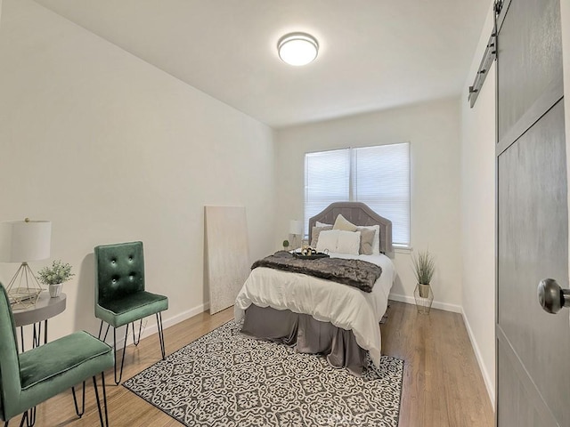 8830 Ruthelen St, Los Angeles, CA 90047 - bedroom with a barn door, light wood-style floors, and baseboards