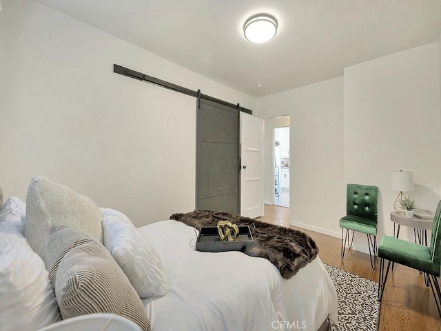 8830 Ruthelen St, Los Angeles, CA 90047 - bedroom featuring a barn door, light wood-style floors, and baseboards