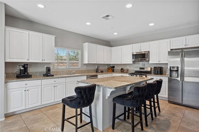 42667 Gazapo Ct, Indio, CA 92203 - kitchen featuring appliances with stainless steel finishes, recessed lighting, white cabinets, a kitchen breakfast bar, and a kitchen island