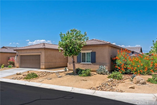 42667 Gazapo Ct, Indio, CA 92203 - view of front of home with an attached garage, stucco siding, a tile roof, and driveway