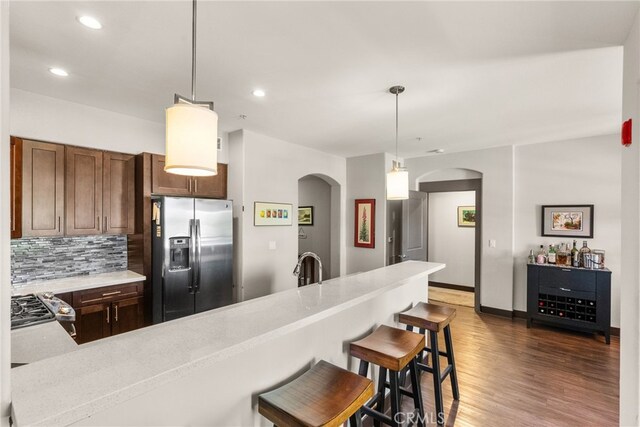 24585 Town Center Dr Unit 4308, Valencia, CA 91355 - kitchen with stainless steel refrigerator with ice dispenser, arched walkways, light countertops, wood finished floors, and backsplash